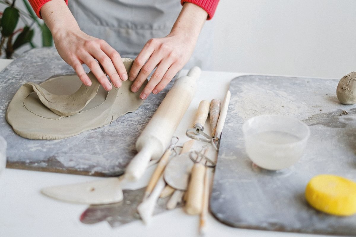 Hands finishing a ceramic vessel on the wheel